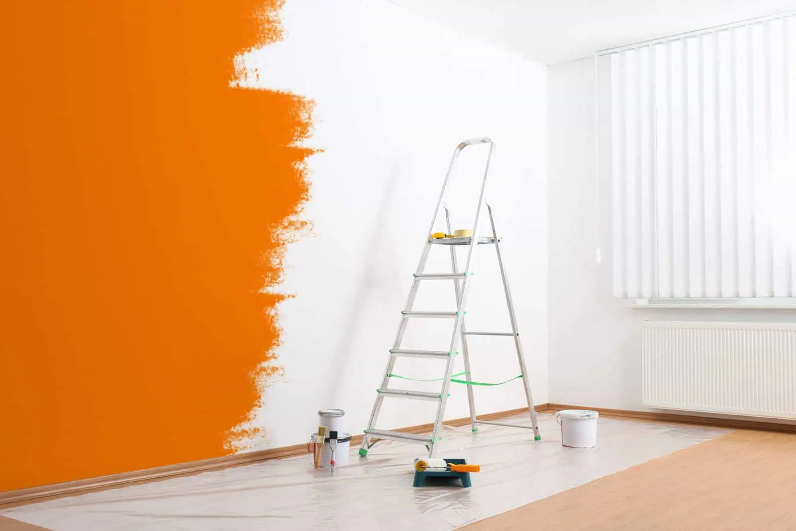 Professional interior wall painting with orange accent wall in progress.
